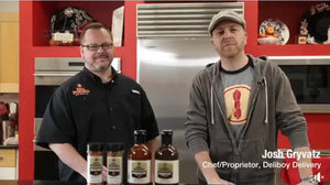 Two chefs in a modern kitchen with Chef Rays BBQ sauces and seasonings on counter.