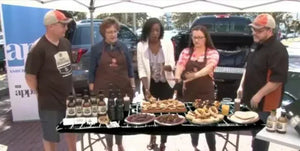 Group of people at a BBQ event displaying Chef Rays LLC sauces and grilled food outdoors.